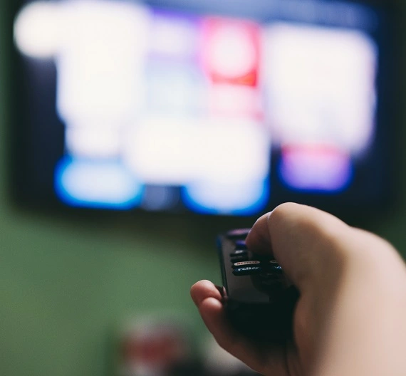 uma pessoa apertando botões do controle remoto para achar códigos da netflix
