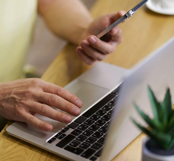 homem mexendo no notebook e no celular pesquisando as tendências do trabalho para o futuro
