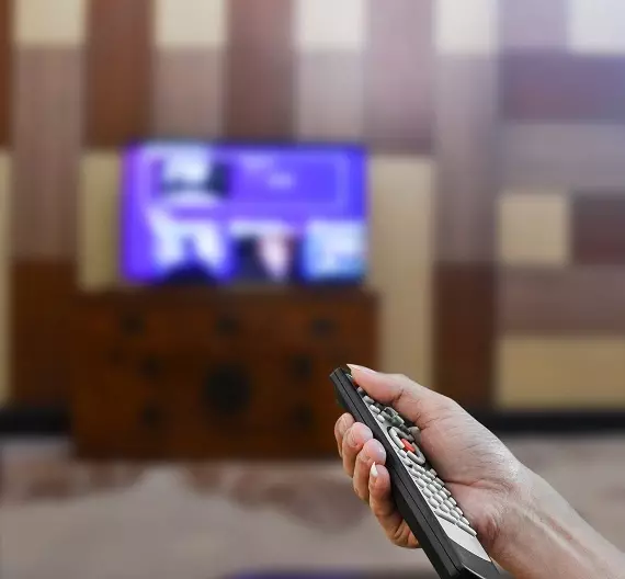 uma pessoa segurando o controle remoto e assistindo a série The Last Of Us